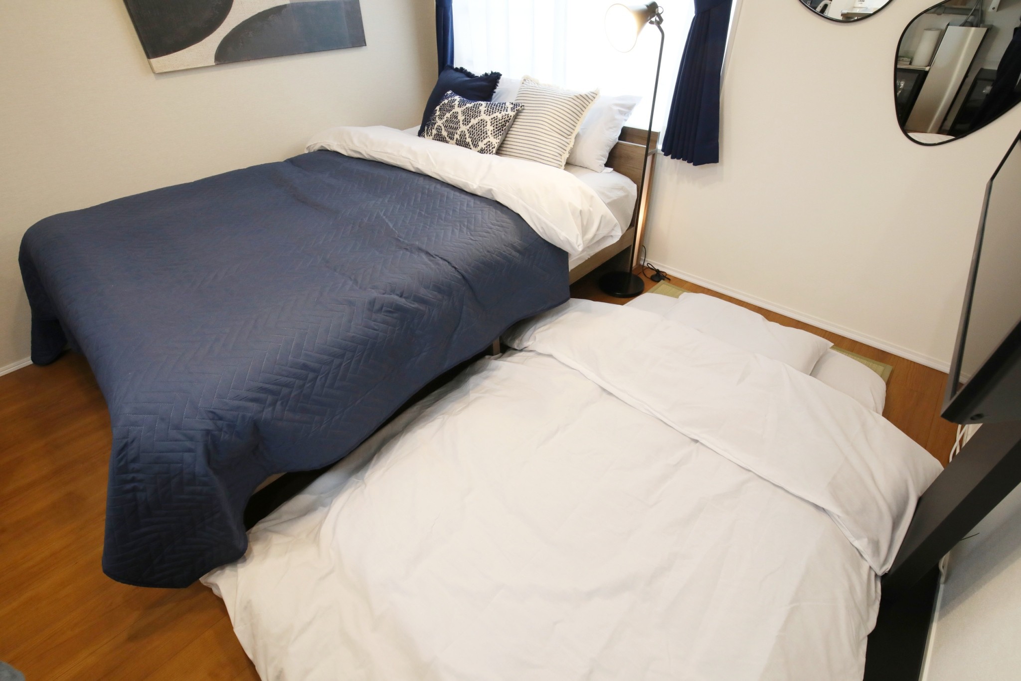Room 202 double bed with round mirror and wall-mounted TV